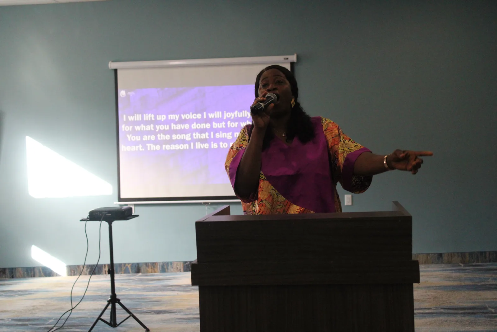 Worship leader singing with lyrics projected on screen